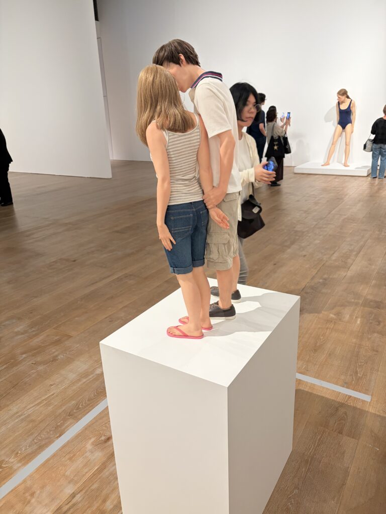 ロン・ミュエク《若いカップル》で少年が少女の手首をつかむ様子